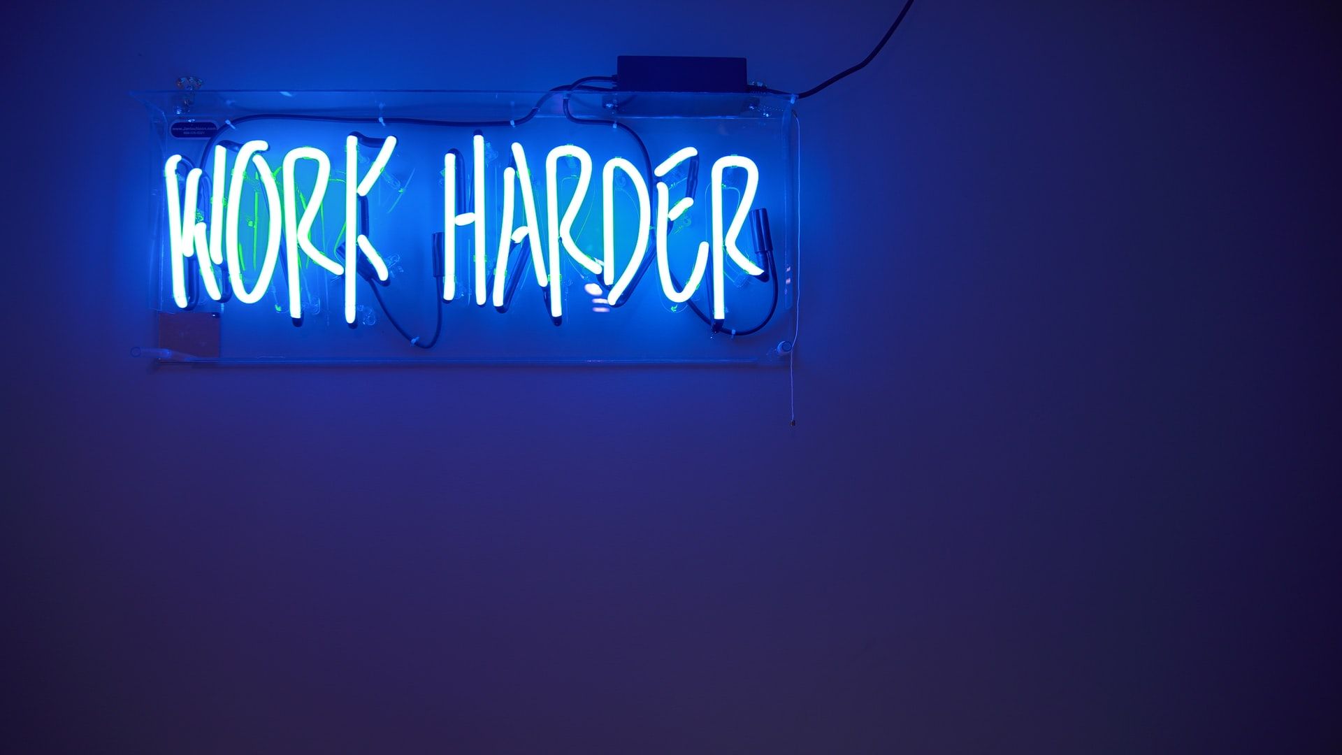 Motivators at work - a neon sign with the slogan work harder
